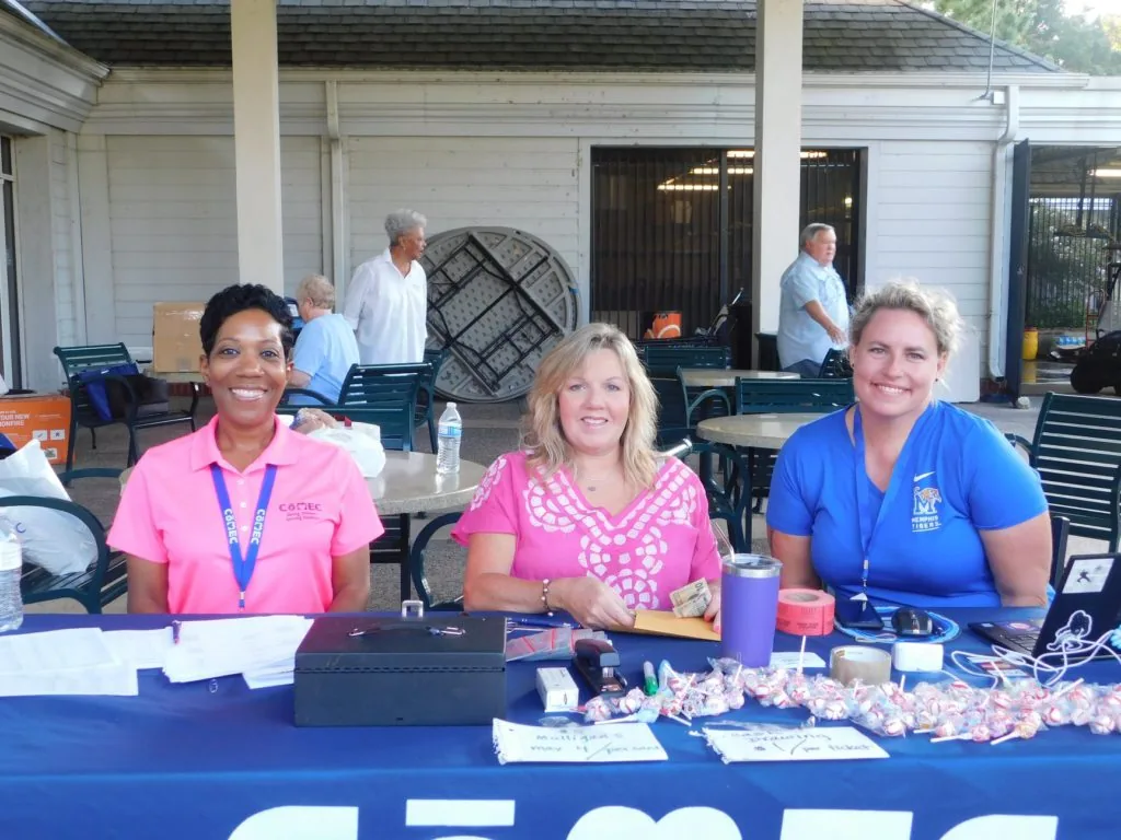 COMEC volunteers welcoming participants at a golf tournament registration table